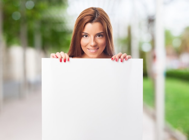 Atrakcyjna kobieta pokazuje białą pustą plakietkę