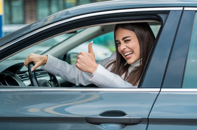 Atrakcyjna kobieta pozuje za kierownicą swojego samochodu
