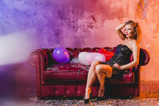 Bezpłatne zdjęcie atrakcyjna kobieta stwarzaję ... cych na kanapie z balonami
