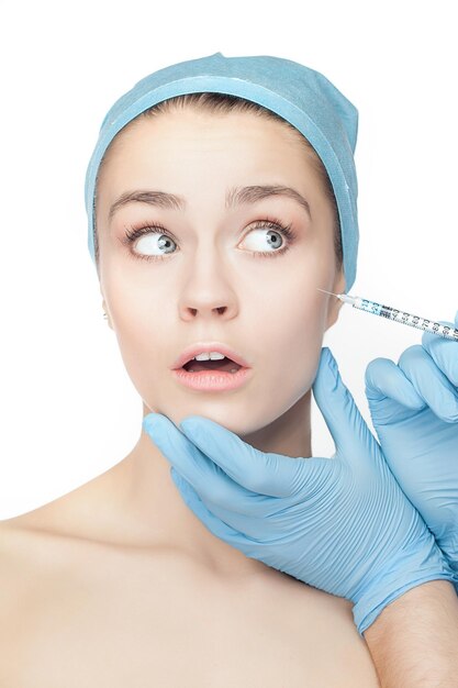 Atrakcyjna kobieta w chirurgii plastycznej ze strzykawką na twarzy