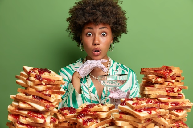 Bezpłatne zdjęcie atrakcyjna kobieta z włosami afro otoczona galaretowatymi kanapkami z masłem orzechowym