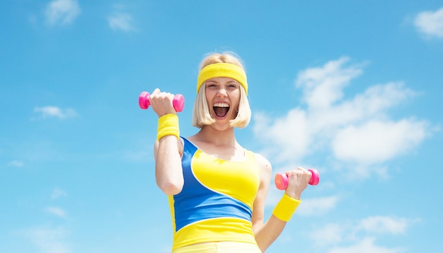 Atrakcyjna młoda kobieta fitness trzyma dumbell kobieta fitness fit kobieta w naturze na wiosnę szczęśliwa k...