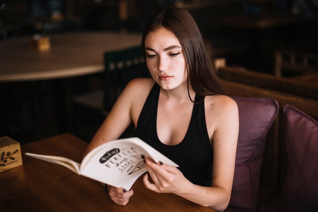 Bezpłatne zdjęcie atrakcyjna młoda kobieta patrzeje menu w restauraci