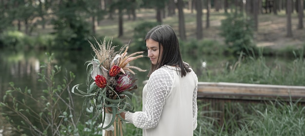 Atrakcyjna młoda kobieta z bukietem kwiatów w lesie nad rzeką