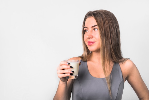Bezpłatne zdjęcie atrakcyjna młoda rozochocona kobieta w sportswear z szkłem mleko
