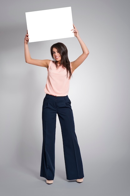 Atrakcyjna modna kobieta trzyma tablicę nad głową