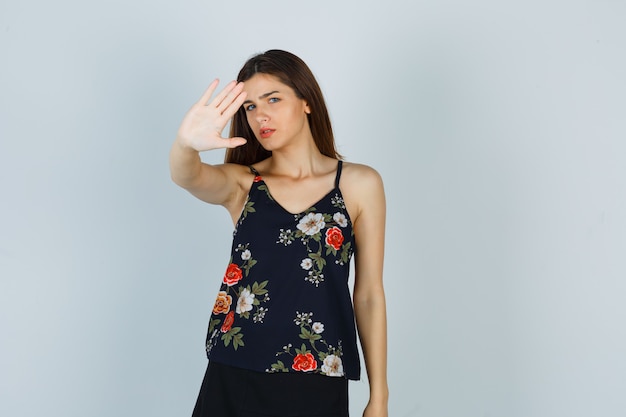 Bezpłatne zdjęcie atrakcyjna pani w bluzce pokazując gest stop i patrząc przestraszony, widok z przodu.