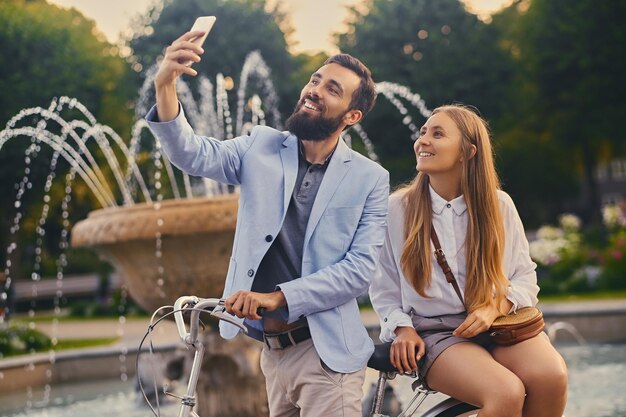 Atrakcyjna para na randkę zrobić selfie na tle fontanny.