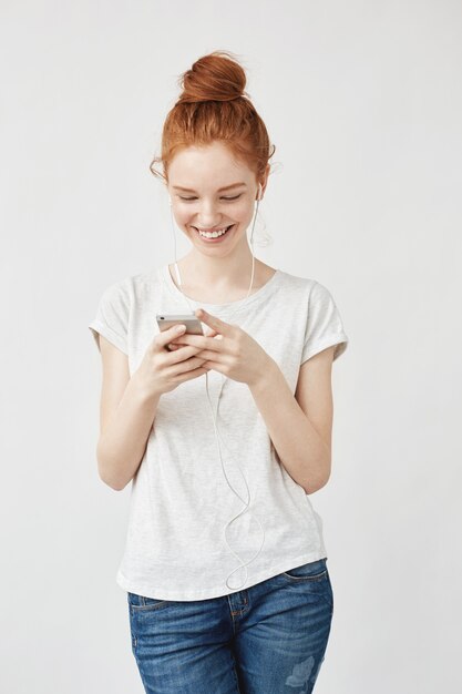 Atrakcyjna rudzielec kobieta ono uśmiecha się z piegami patrzeje telefon.