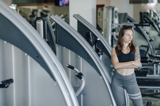 Bezpłatne zdjęcie atrakcyjna wysportowana dziewczyna stoi na ścianie symulatorów na siłowni. zdrowy tryb życia.