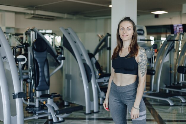 Atrakcyjna wysportowana dziewczyna stoi na ścianie symulatorów na siłowni. zdrowy tryb życia.