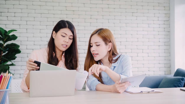 Atrakcyjne mądrze kreatywnie Azjatyckie biznesowe kobiety w mądrze przypadkowej odzieży pracuje na laptopie podczas gdy siedzący