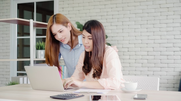 Atrakcyjne mądrze kreatywnie Azjatyckie biznesowe kobiety w mądrze przypadkowej odzieży pracuje na laptopie podczas gdy siedzący