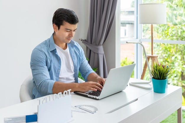 Atrakcyjny mężczyzna pracuje w domu z laptopem na laptopie