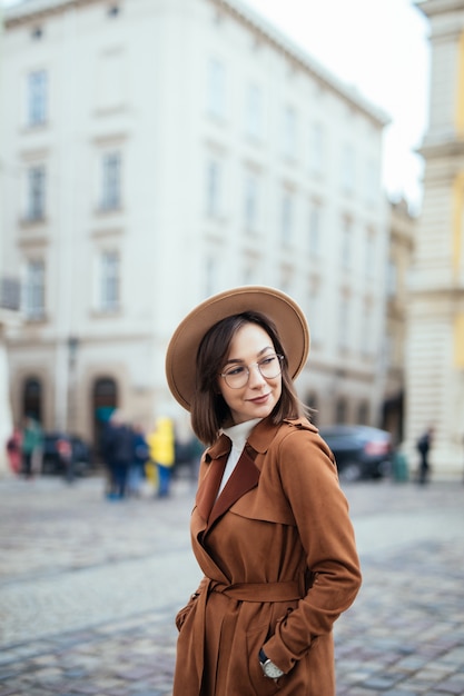 Atrakcyjny w nowoczesnym brązowym płaszczu pozowanie na ulicy w centrum miasta