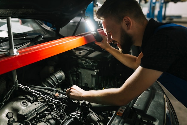 Auto mechanik patrząc na silnik samochodu