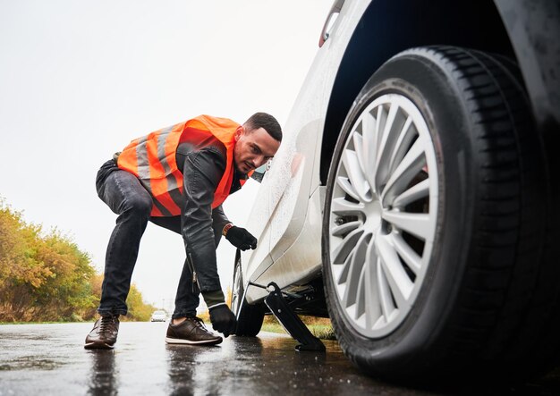 Awaryjny pojazd podnoszący mechanika z podnośnikiem samochodowym na ulicy