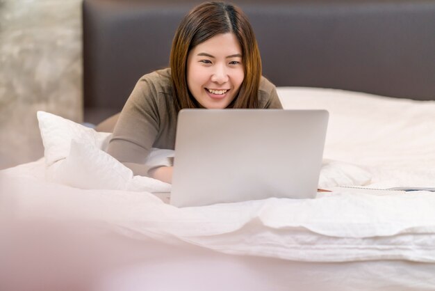 Azjatycka kobieta biznesu korzystająca z laptopa technologicznego i pracująca w domu w sypialni w pomieszczeniu