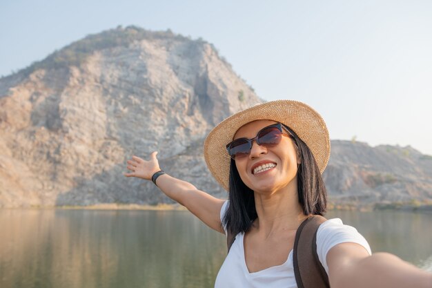Azjatycka kobieta blogerka z plecakiem używająca smartfona przy selfie