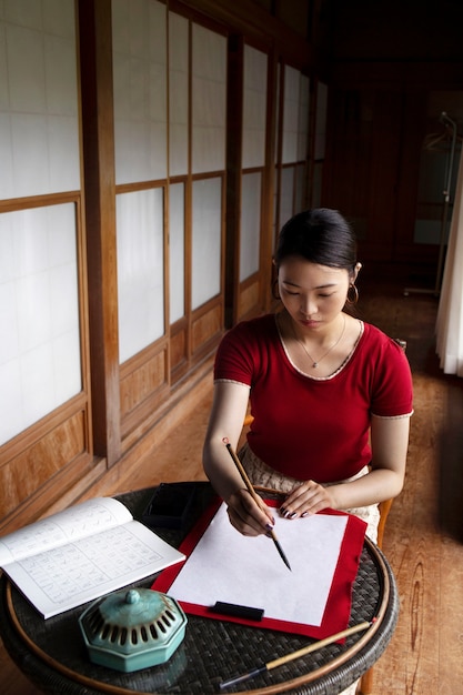 Bezpłatne zdjęcie azjatycka kobieta ćwicząca japońskie pismo odręczne w pomieszczeniu