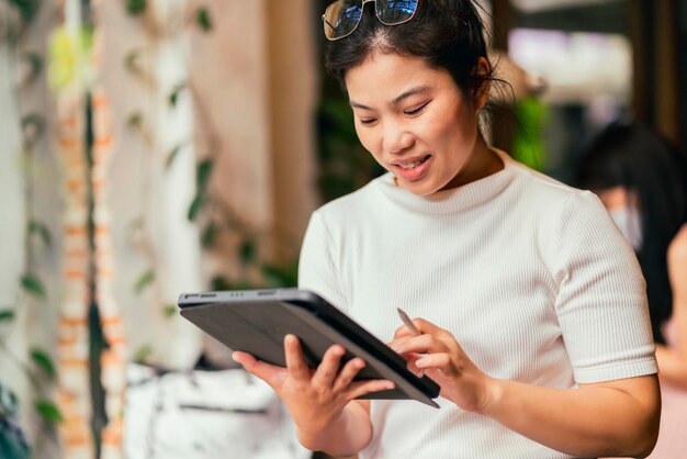 Azjatycka kobieta niezależna cyfrowa nomada kariera szczęście praca wesoła uśmiechnięta praca online z inteligentnym urządzeniem tablet smartfon za granicą zawód projekt praca w dowolnym miejscu nowy bezramkowy styl życia