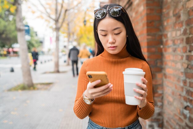 Azjatycka kobieta używa jej telefon komórkowego.