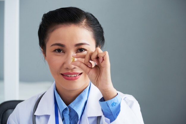 Azjatycka kobiety lekarki mienia pigułka przed jej twarzą