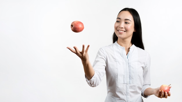 Azjatycka Młoda Kobieta żongluje Z Dwa Czerwonymi Jabłkami