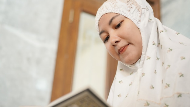 Azjatycka muzułmanka czytająca koran w meczecie