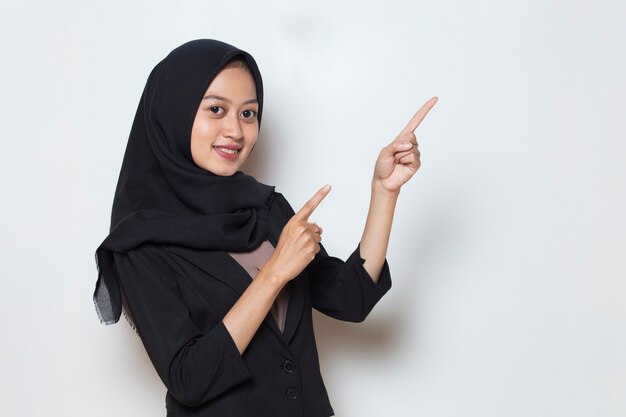 Azjatycka muzułmańska biznesowa kobieta wskazująca palcami w różnych kierunkach kopiuje miejsce na reklamę