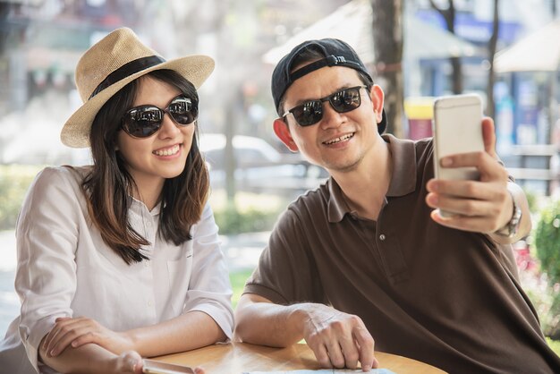 Azjatycka para cieszy się podróżować obsiadanie przy sklep z kawą