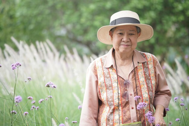 Azjatycka starsza starsza starsza kobieta odpoczywa relaksując się w różanym ogrodzie kwiatowym
