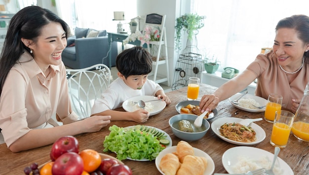 Bezpłatne zdjęcie azjatycka szczęśliwa rodzina spędza czas jedząc obiad na stole razem, związek i aktywność w domu