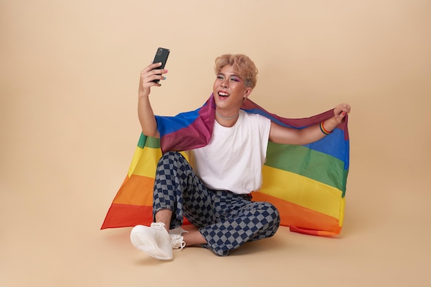 Bezpłatne zdjęcie azjatycka transpłciowa lgbt trzymająca smartfon w ręku, strzelająca do selfie przednim aparatem