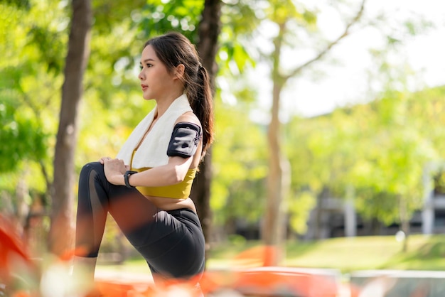 Azjatycka wesoła młoda osoba dorosła Atrakcyjny i silny poranny rozciągający się przed bieganiem w parku Koncepcja sportu Zdrowy styl życia Młoda kobieta fitness biegacz rozciągający się przed biegiem w parku