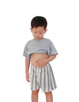 Azjatycki chłopiec dziecko w wieku około 3 lat podnosząc jego koszulę pokaż odsłaniając jego duży brzuch na białym tle ze ścieżką przycinającą