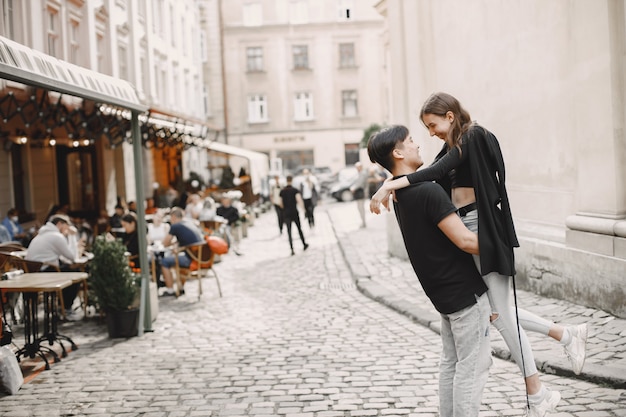 Azjatycki chłopiec i jego kaukaska dziewczyna w stroju casual stojący na ulicy Lwowa. Para przytula się podczas wspólnego spaceru po mieście