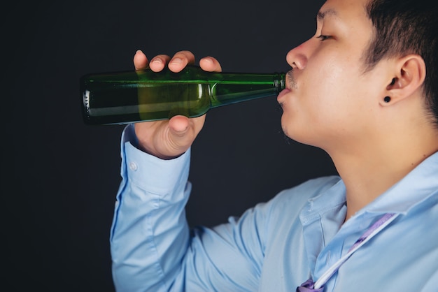 Bezpłatne zdjęcie azjatycki człowiek pije butelkę piwa