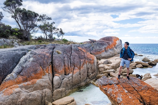 Azjatycki mężczyzna pozuje w Zatoce Ognia na Tasmanii w Australii