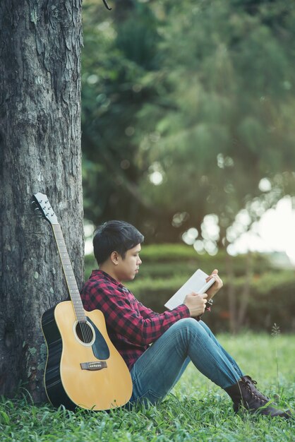 Azjatycki mężczyzna z gitarą akustyczną w parku