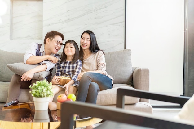Azjatyckie szczęście Rodzina rozmawiająca i relaksująca się na kanapie oglądanie telewizji razem