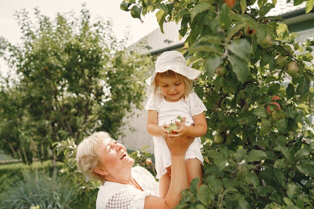 Babcia i wnuczka razem przytulające się i radośnie śmiejące się w kwietniowym ogrodzie kwitnących moreli. Rodzinny styl życia na świeżym powietrzu.