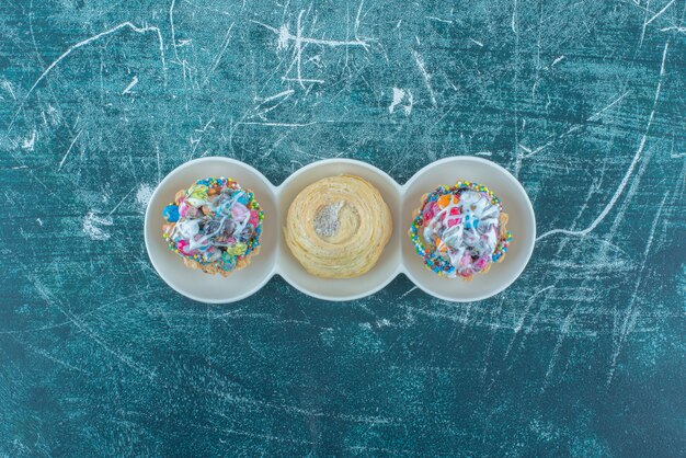 Babeczki i ciasteczka w małym talerzu porcji na niebieskim tle. Wysokiej jakości zdjęcie