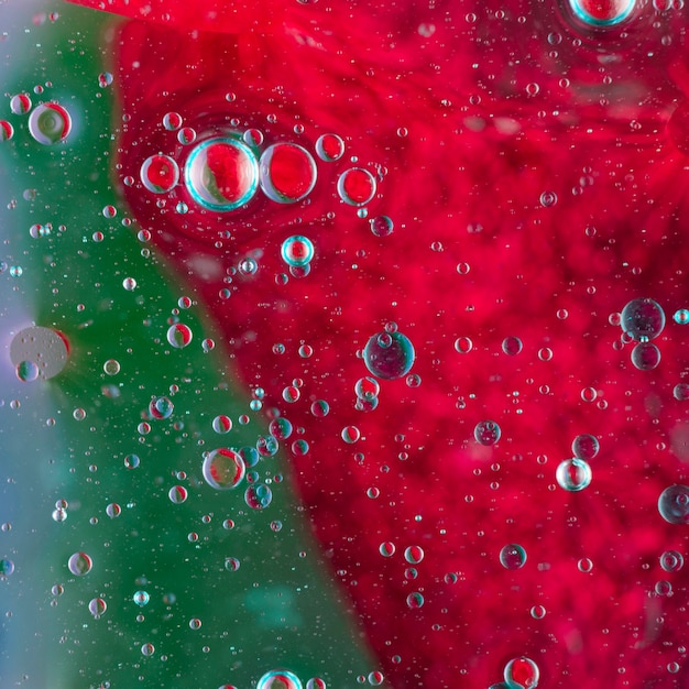 Bąbelki oleju unoszące się na zielonej i czerwonej powierzchni wody