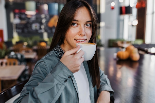 Bardzo młoda kobieta, ciesząc się filiżanką kawy
