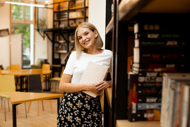 Bardzo młoda kobieta pozuje w bibliotece