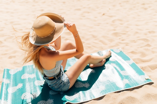 Bardzo młoda kobieta siedzi na piasku na plaży