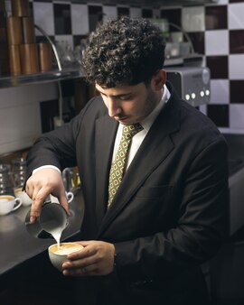 Barista practicando latte art en una taza de cafe con leche de la cafeteria
