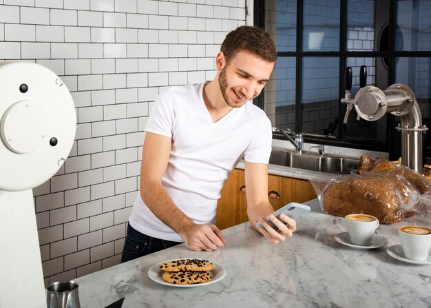 Barista stojący z smartphone za ladą