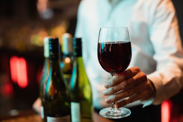 Barman trzyma kieliszek czerwonego wina